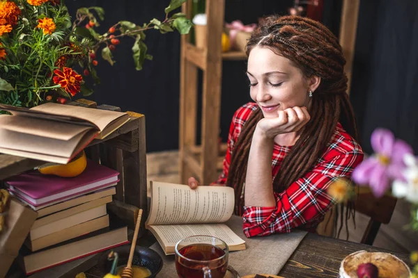 Femme lisant un livre romantique dans l'atmosphère automnale. Table rustique avec des fleurs jaunes et une pile de livres. Humeur d'automne — Photo