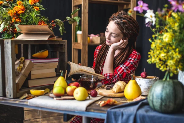 Femme lisant un livre romantique dans l'atmosphère automnale. Table rustique avec des fleurs jaunes et une pile de livres. Humeur d'automne — Photo