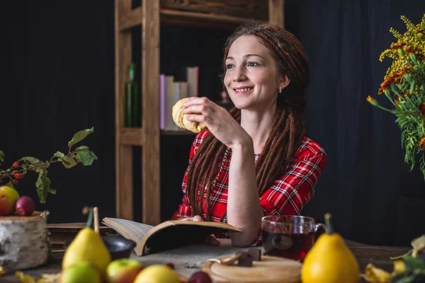 Mujer leyendo un libro romántico en un ambiente acogedor y cálido disfrutando del ambiente otoñal. Mesa rústica con pila de libros — Foto de Stock