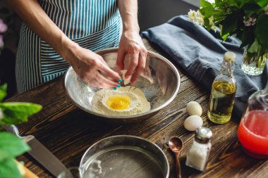 Bir kadın para kazanmak için yumurta kırıyor. Hoş ve rahat bir ev ortamında el yapımı makarna yapma süreci.