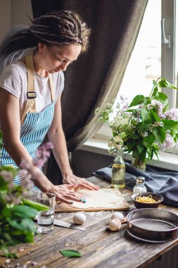 Kadın sıcak bir atmosferde makarna yapmak için taze hamur çıkarıyor. Evde lezzetli yemekler pişirme kavramı
