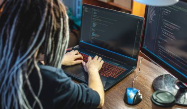 Modern genç bayan programcı evdeki bir dizüstü bilgisayara program kodu yazıyor. Uzaktan kumandalı bilişim işi. Yazılım geliştirme kavramı.