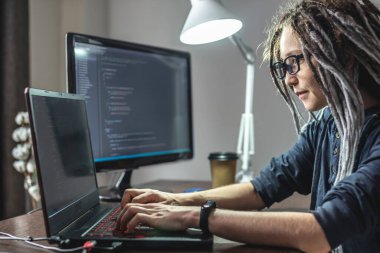 Modern genç bayan programcı evdeki bir dizüstü bilgisayara program kodu yazıyor. Uzaktan kumandalı bilişim işi. Yazılım geliştirme kavramı.