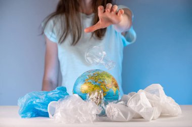 Kadın naylonu Dünya 'ya çöp yığınının içindeki bir küre şeklinde atıyor. Çevre kirliliği ve gezegeni kurtarma kavramı