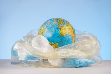 Plastik çöplerin arasında çöp torbasında küre şeklinde bir dünya. Çevre kirliliği ve gezegeni kurtarma kavramı