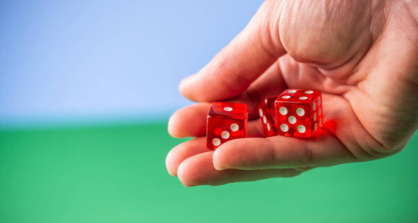 A hand is holding red dice over a green table