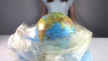 Kadın Dünya 'yı plastik bir çöp yığınından bir küre halinde çıkarıyor. Çevre kirliliği ve gezegeni kurtarmak
