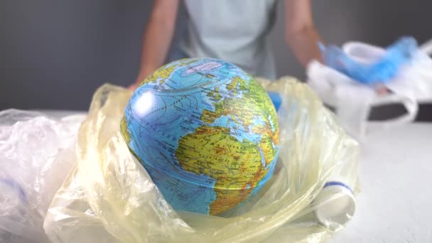 La donna sta mettendo la Terra sotto forma di un globo in un sacco della spazzatura con plastica. Inquinamento ambientale e risparmio del pianeta — Video Stock