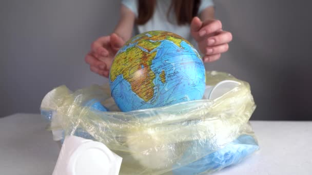 La mujer está sacando una Tierra en forma de globo de una pila de basura plástica. Contaminación ambiental y salvamento del planeta — Vídeo de stock