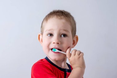 Küçük bir çocuk diş fırçası kullanarak dişlerini fırçalamayı öğreniyor. Çocuk hijyeni ve bağımsızlık kavramı.