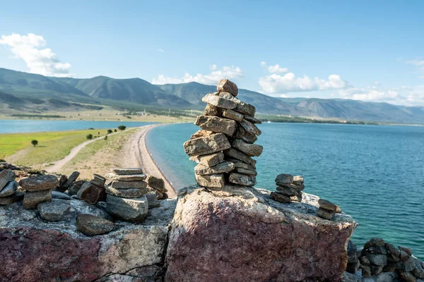 Pile of stones built in cairn on the background of lake Baikal. Concept of calmness and detachment with nature