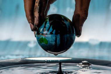 Kirli adamın eli, Dünya 'yı petrolden bir küre şeklinde çıkarıyor. Gezegeni kurtarma, doğal kaynakları kullanma ve çevreye zarar verme kavramı