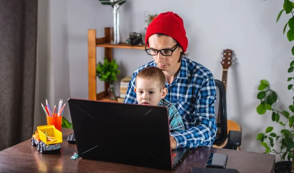 Νεαρός Σύγχρονος Πατέρας Εργάζεται Ένα Φορητό Υπολογιστή Και Μικρός Γιος — Φωτογραφία Αρχείου