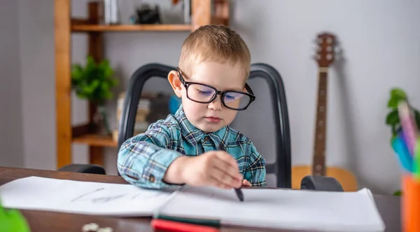 可爱的小男孩在桌上的相册里用粉笔在纸上画画 学前教育的概念和创造力的发展 — 图库照片