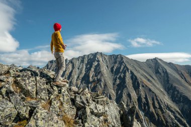 Erkek turistler, güneşli bir günde kollarını dağların arkasında açarak başarıyı kutluyorlar. Motivasyon ve hedeflerine ulaşma kavramı
