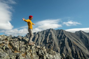 Erkek turistler, güneşli bir günde kollarını dağların arkasında açarak başarıyı kutluyorlar. Motivasyon ve hedeflerine ulaşma kavramı