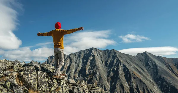 Erkek turistler, güneşli bir günde kollarını dağların arkasında açarak başarıyı kutluyorlar. Motivasyon ve hedeflerine ulaşma kavramı