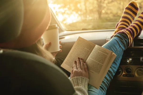 暖かいウールの靴下の黄色の車の中で女性は日没時に助手席に座って本を読んでいます 素敵な秋の週末旅行 旅の自由の概念 — ストック写真