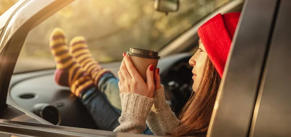 Sıcak yün çoraplı bir kadın gün batımında elinde bir fincan kahve tutuyor. Sıcak sonbahar hafta sonu gezisi. Seyahat özgürlüğü kavramı
