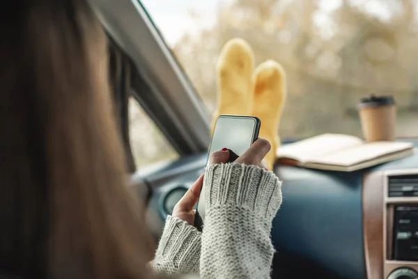 Wanita Dalam Mobil Kaus Kaki Yang Hangat Memegang Sebuah Gadget Stok Foto