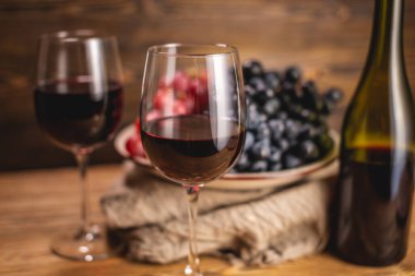 Bir şişe kırmızı şarap, bir bardak ve bir demet üzümle ahşap bir masada. Eklem ve şarap üretimi kavramı