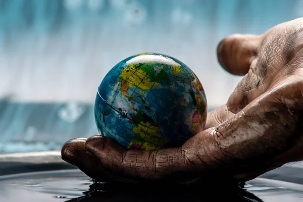 Kirli adamın eli Dünya 'yı petrolden bir küre halinde çıkardı ve dikkatlice tutuyor. Çevre dostu davranış kavramı, doğal kaynakları kullanmak ve çevreye zarar vermek