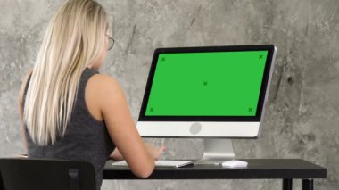 Office masaüstü monitör çalışma masasında oturan işkadını. Yeşil perde Mock-up göstermek.