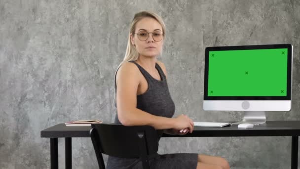 Stolta frilansande kvinna poserar på kontoret och tittar på dig. Visa till datorskärm. Mock-up-grön skärm. — Stockvideo