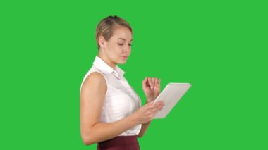 Modern işkadını Chroma anahtar yeşil ekran yürürken tablet bilgisayar kullanarak.