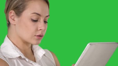 Bir tablet bilgisayar Chroma anahtar yeşil ekran tutan genç çekici iş kadın.