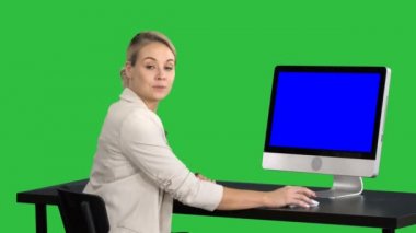 Kameraya konuşmaya ve bir şey Chroma anahtar yeşil ekranda bilgisayarın ekranında gösterilen genç güzel bayan. Mavi ekran Mock-up.