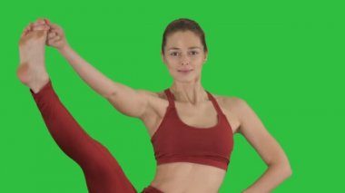 Güzel genç kadın ayakta Böl-urdhva prasarita Eka padasana Chroma anahtar yeşil ekranda.