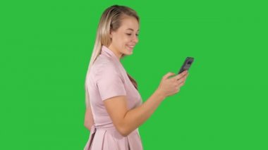 Mutlu kadın Chroma anahtar yeşil ekranda bir akıllı telefon içeriğinde satırı seçme.