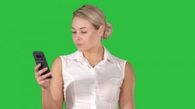 Genç kız Chroma anahtar yeşil ekranda cep telefonu ekranından okuma.