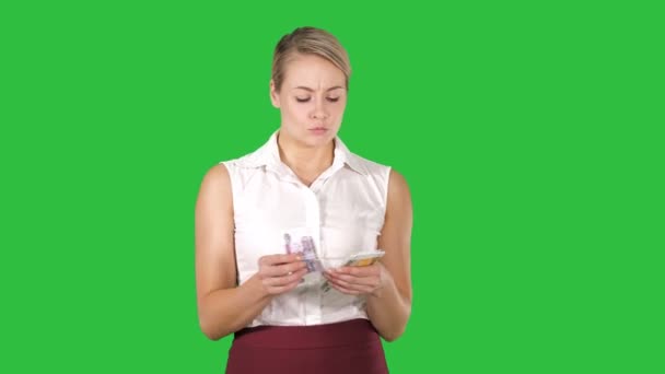 Attraktive junge Frau zählt Geld, was sie auf einem grünen Bildschirm ausgeben soll, Chroma-Schlüssel. — Stockvideo