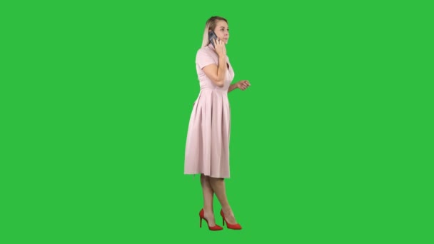 Mooi meisje in een roze jurk op de telefoon op een groen scherm, Chromakey. — Stockvideo