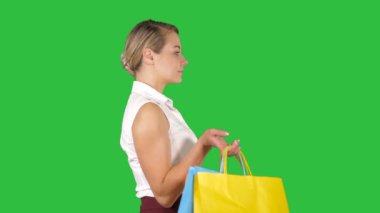 Alışveriş torbaları Chroma anahtar yeşil ekran yürüyüş olan mutlu kadın.