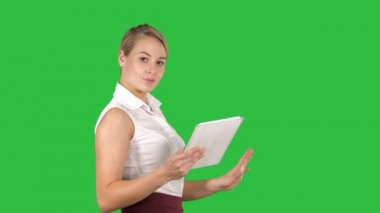 Tablet ile yürüyüş ve geniş kamera için Chroma anahtar yeşil ekran konuşurken gülümseyen kadın büro memuru.