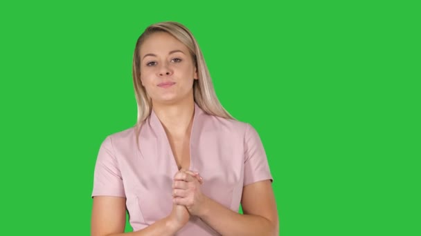 Hübsche schöne Frau mit blonden Haaren in rosa gekleidet, die auf einem grünen Bildschirm läuft und spricht, Chroma-Schlüssel. — Stockvideo