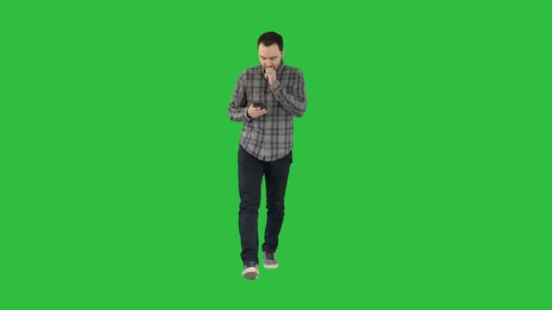 Surprised young man is holding phone and reading message on a Green Screen, Chroma Key. — Stock Video