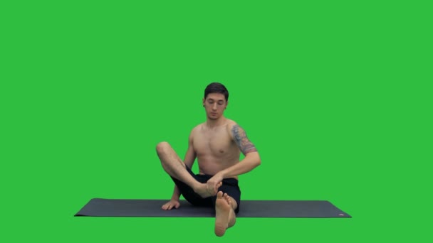 Junger Mann praktiziert Yoga in Halb-Held-Stretch-Pose auf einem grünen Bildschirm, Chroma-Taste. — Stockvideo