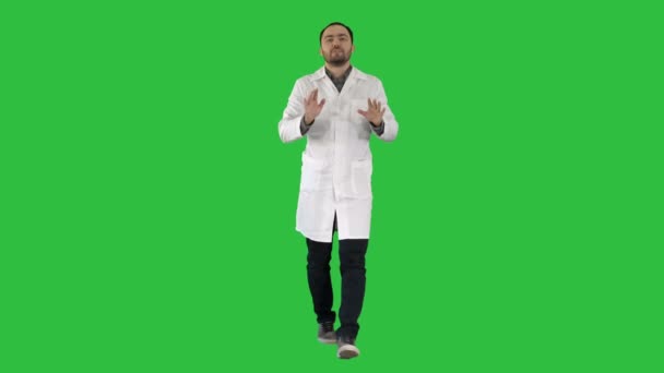 Fröhliche Ärztin beim Gehen, Reden und Blicken in die Kamera auf einem grünen Bildschirm, Chroma-Taste. — Stockvideo