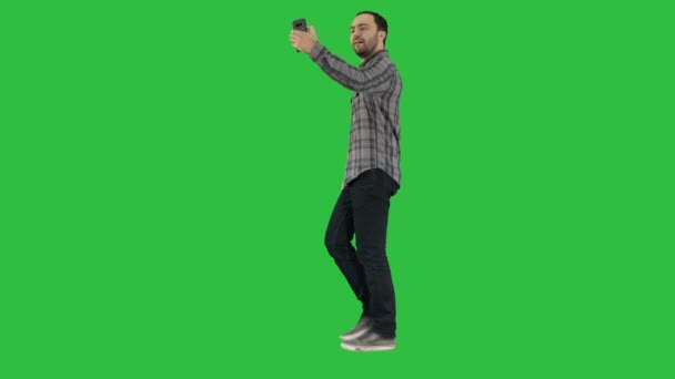 Glücklich lächelnd spazierend schöner bärtiger junger Mann macht Selfie auf einem grünen Bildschirm, Chroma-Schlüssel. — Stockvideo