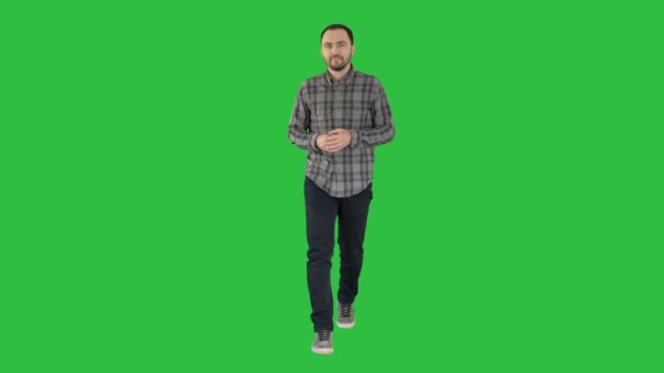 Юнак впевнено в сорочці і джинси, що йде у напрямку камери і вказуючи боків на зелений екран, Chroma Key. — стокове відео
