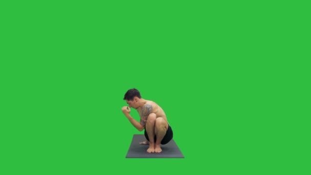 Νεαρός κάνει squat με συστροφή και κάμψη γιόγκα σε μια πράσινη οθόνη, Chroma Key. — Αρχείο Βίντεο