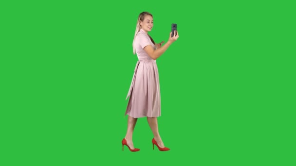 Junge Frau in rosa mit Smartphone-Video-Blog-Aufnahme während des Gehens auf einem grünen Bildschirm, Chroma-Schlüssel. — Stockvideo