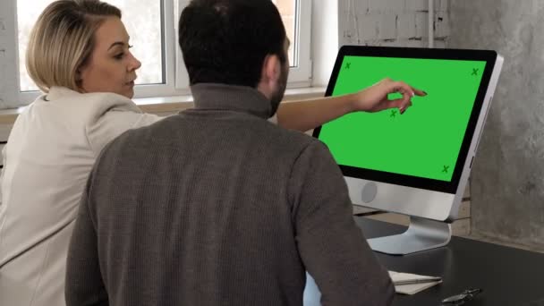 Dois jovens empresários a ter uma reunião no escritório a ver no monitor. Tela verde Mock-up Display . — Vídeo de Stock