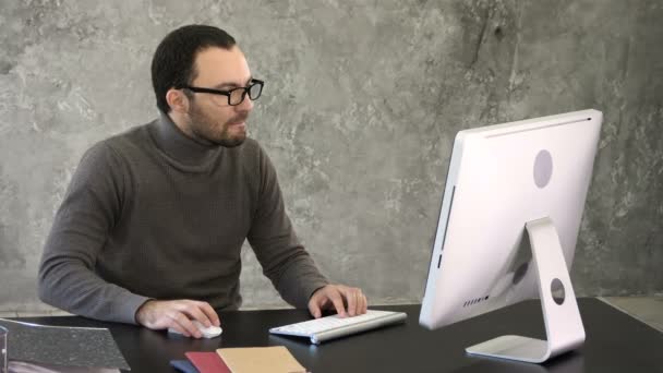 Uomo d'affari occasionale che lavora in ufficio, seduto alla scrivania, digitando sulla tastiera, guardando lo schermo del computer. — Video Stock