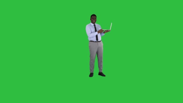 Talking to camera young african man with laptop in his hands on a Green Screen, Chroma Key. — Stock Video