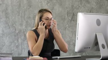 Ofiste oturan iş kadını cep telefonuyla konuşuyor..